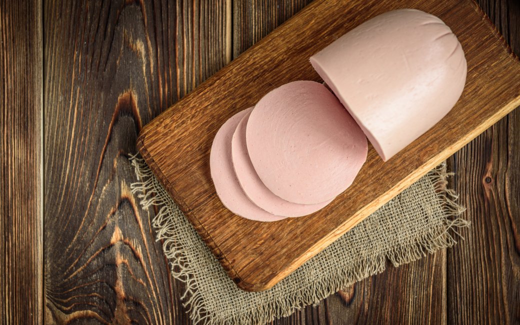 Палка вареної ковбаси на обробній дошці