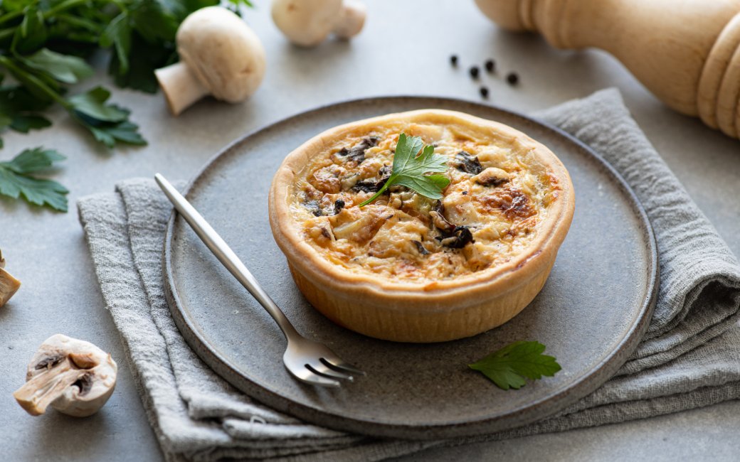Кіш з грибами та куркою на сірій тарілці