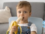 Хлопчик їсть фрукт