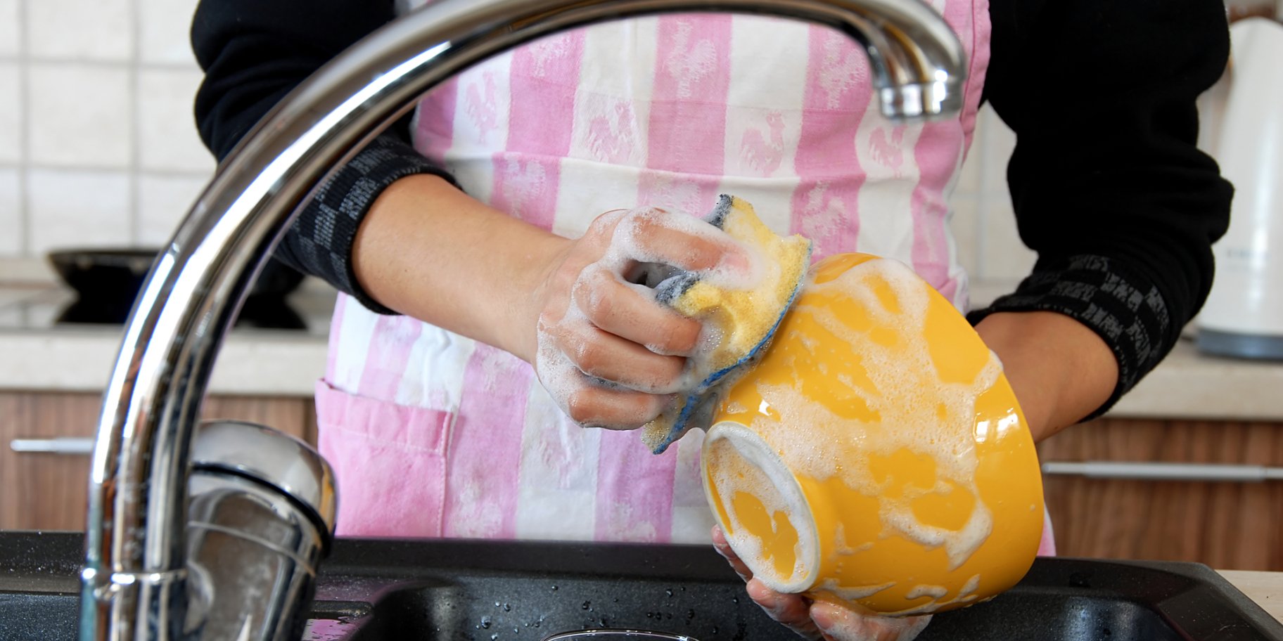 Жінка миє посуд