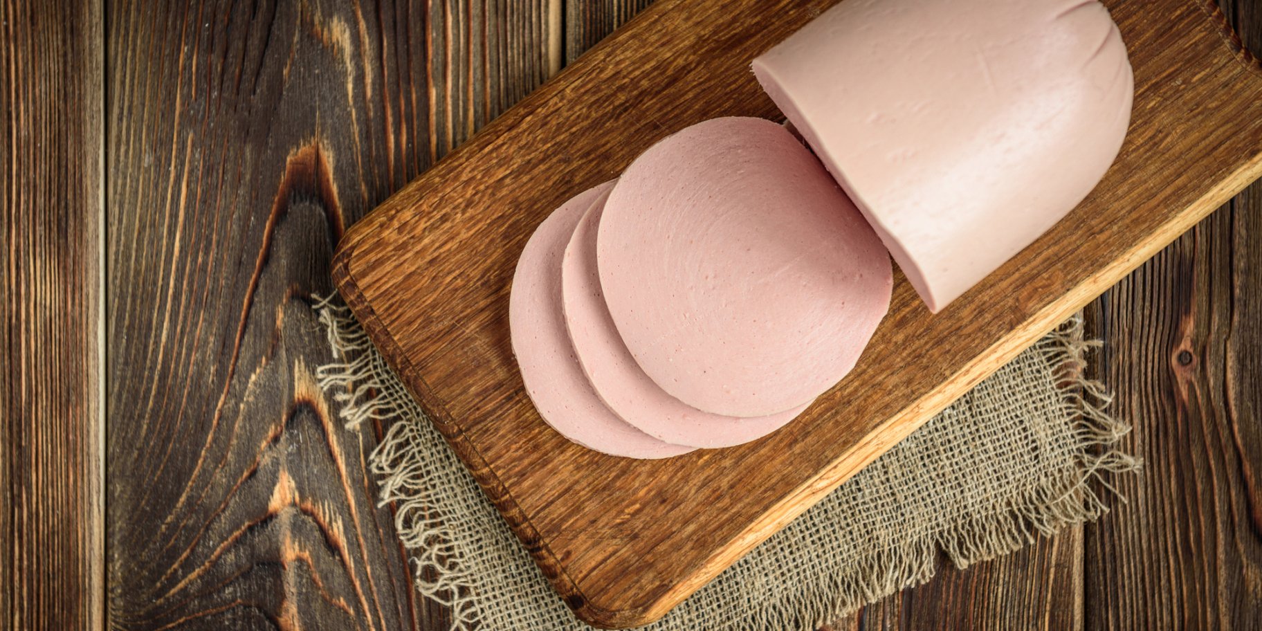 Палка вареної ковбаси на обробній дошці