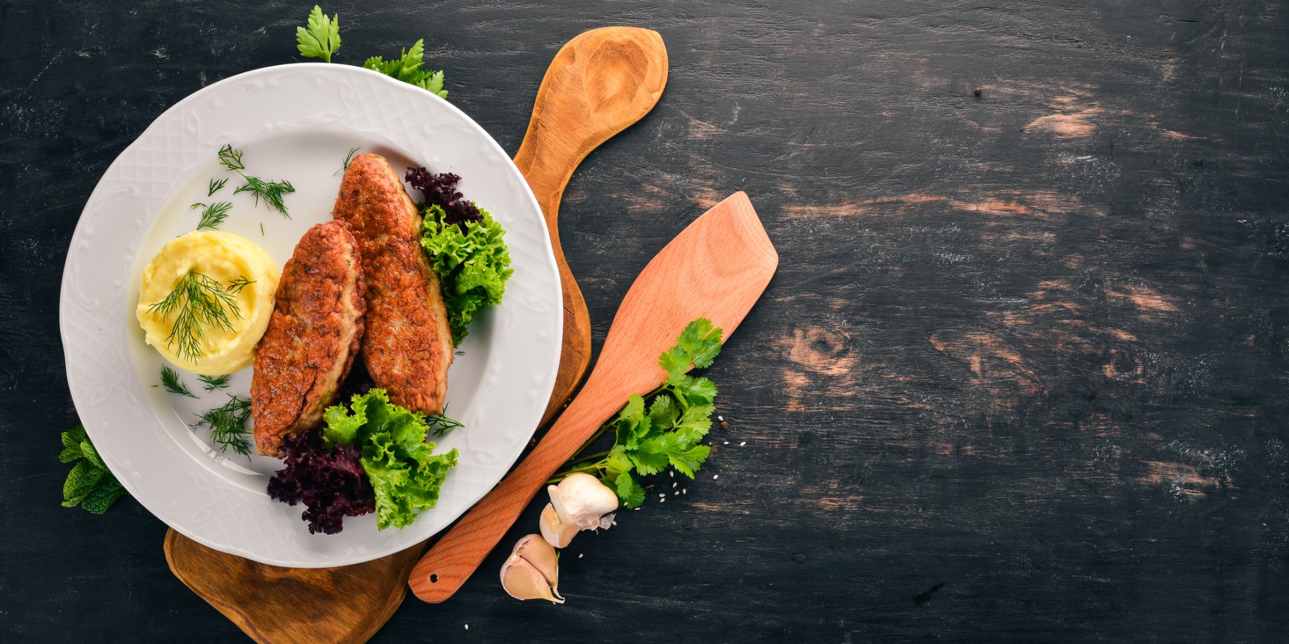 Котлети з пюре на білій тарілці на фоні чорного стола