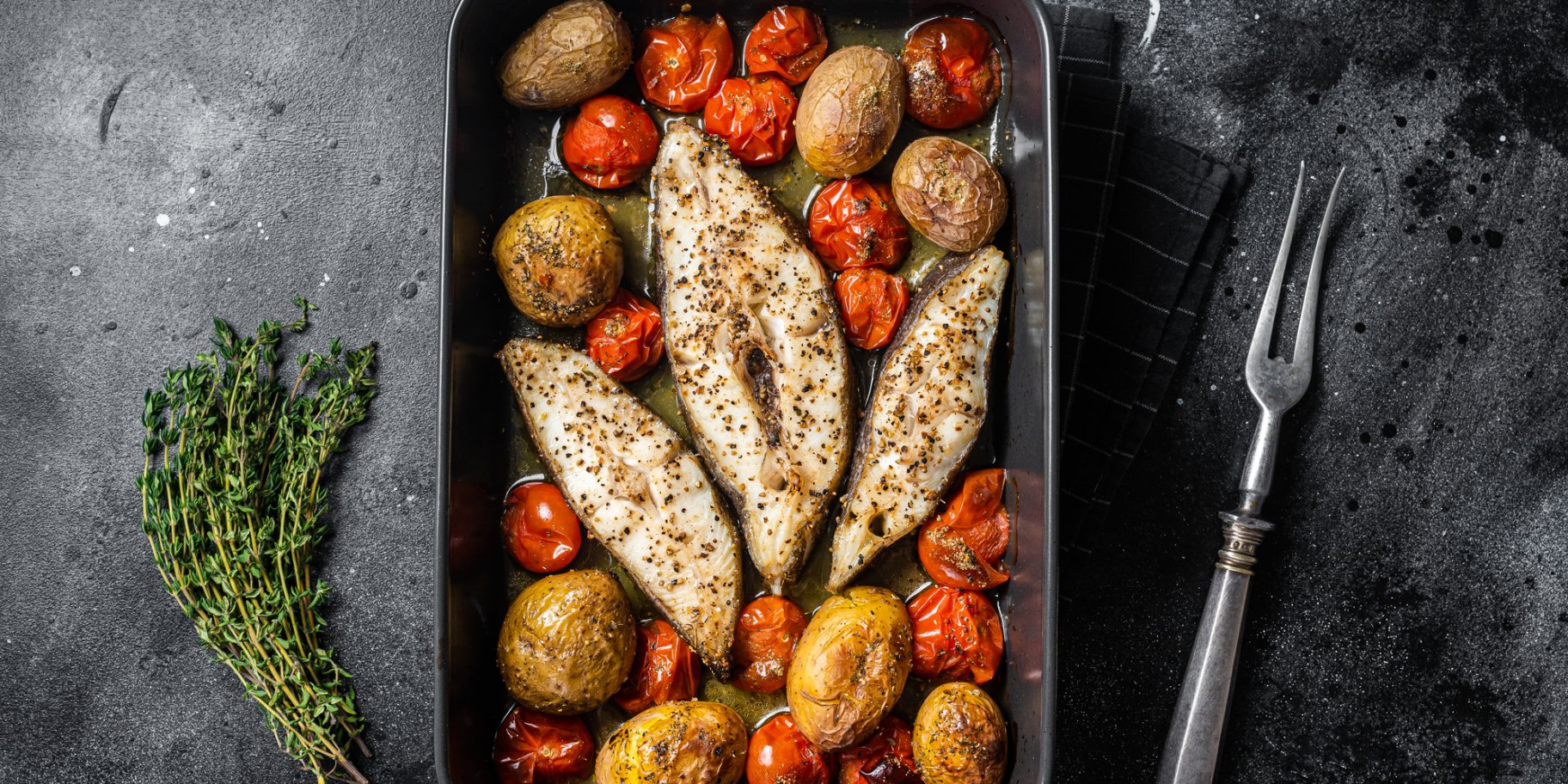 Три стейки палтуса, запечені з овочами, у чорній формі