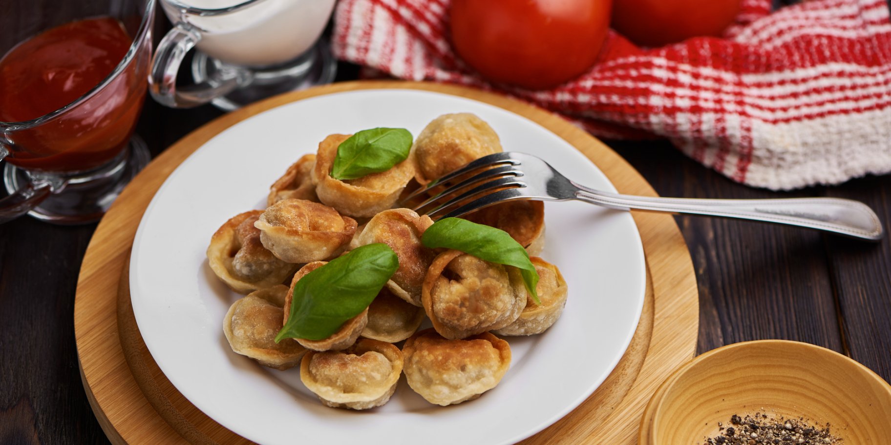 Смажені пельмені з базиліком на білій тарілці