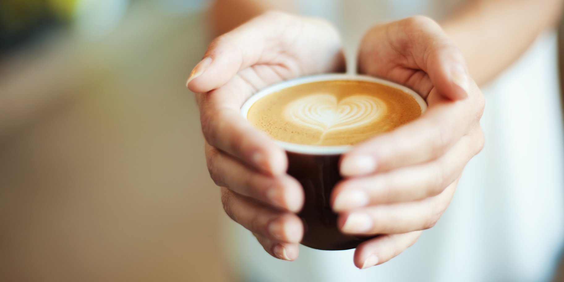 Женщина, держащая в руках чашку с кофе.