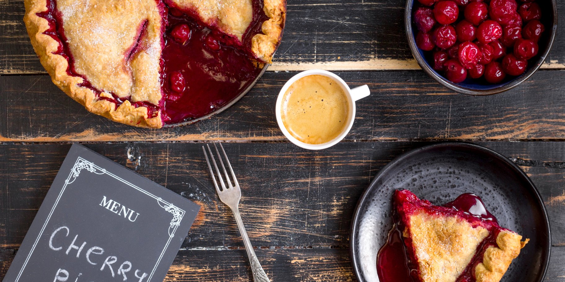 Вишневий пиріг, тарілка з вишнями, шматок вишневого пирога та чашка кави на дерев'яному столі