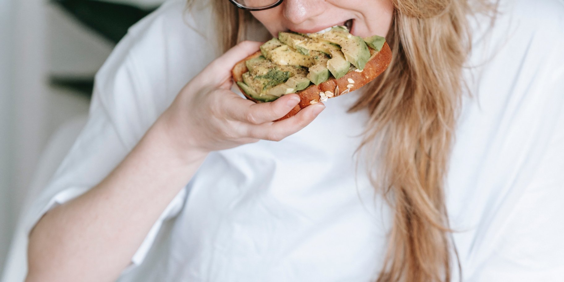 Жінка їсть тост з авокадо