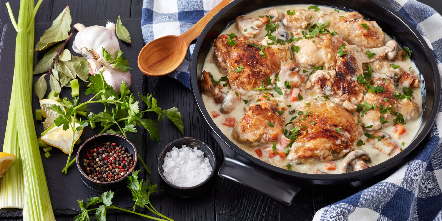 Курячі стегна у вершково-винному соусі в чорній тарілці з селерою та часником