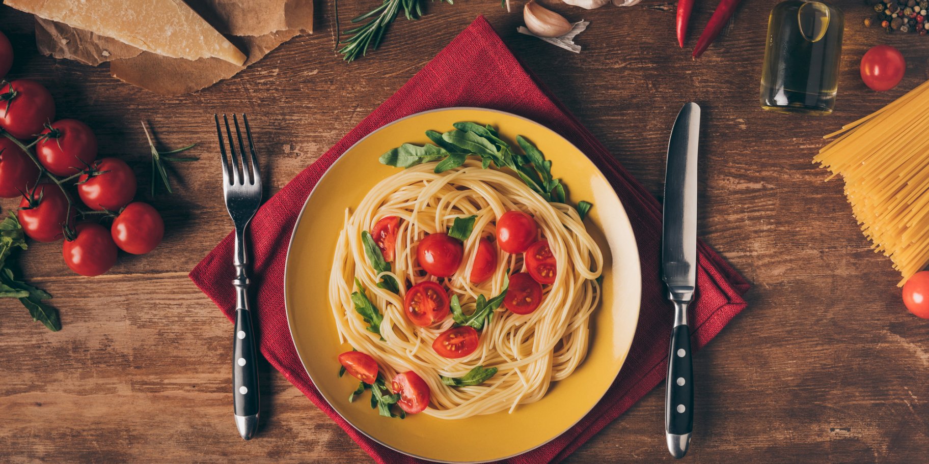 Паста в желтой тарелке с ножом и вилкой