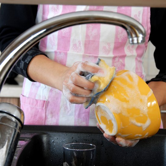 Жінка миє посуд