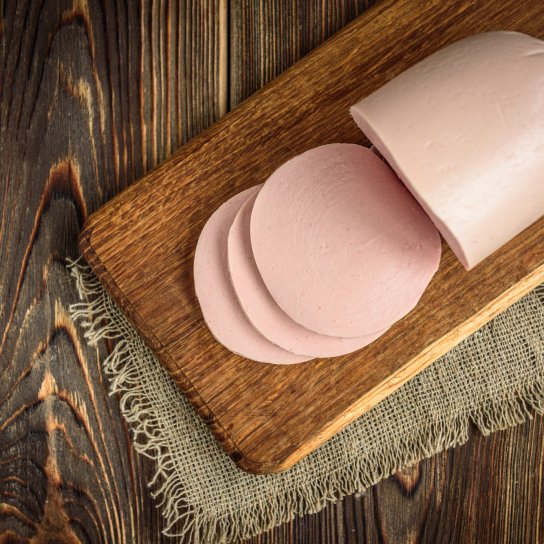 Палка вареної ковбаси на обробній дошці