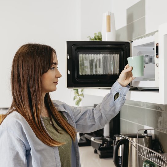 Дівчина використовує мікрохвильову піч