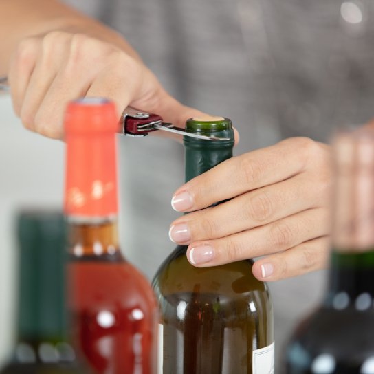 Жінка відкорковує вино