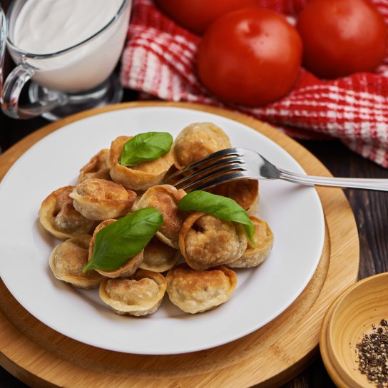 Смажені пельмені з базиліком на білій тарілці