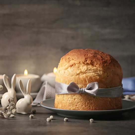 Паска, перев'язана стрічкою на темному фоні зі свічками та кроликами