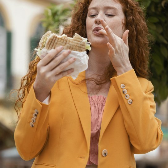 Дівчина їсть вуличну їжу