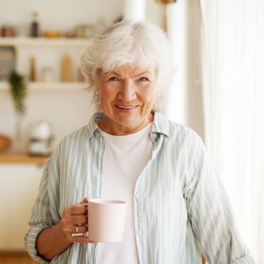 Літня жінка п'є чай