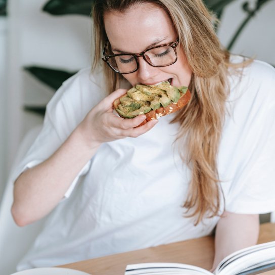 Жінка їсть тост з авокадо