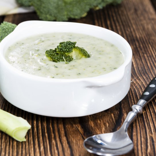 Крем-суп з броколі у білій мисці на дерев'яному столі