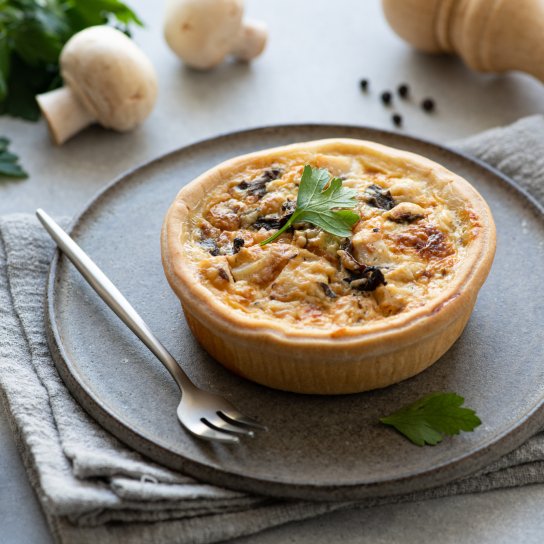 Кіш з грибами та куркою на сірій тарілці