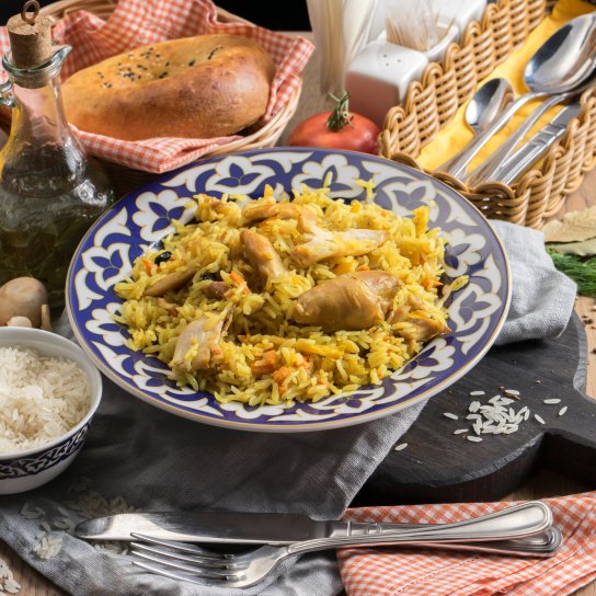 Плов з курячим м'ясом на тарілці зі спеціями та овочами