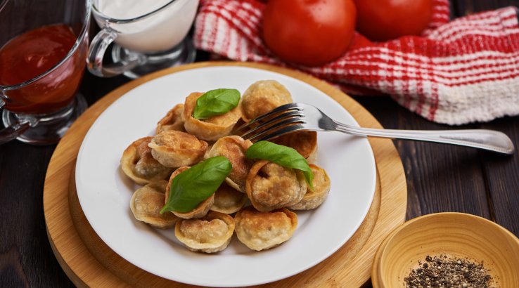 Смажені пельмені з базиліком на білій тарілці