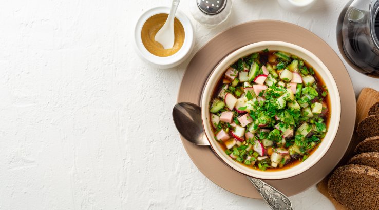 Холодный суп с килькой в томате на тарелке на белом фоне